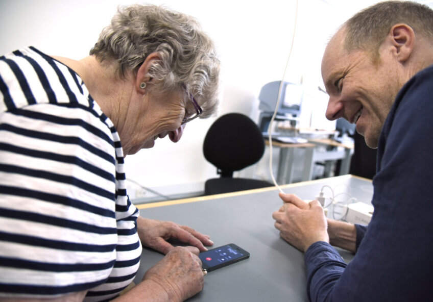 To personer sidder sammen og kigger på en mobiltelefon