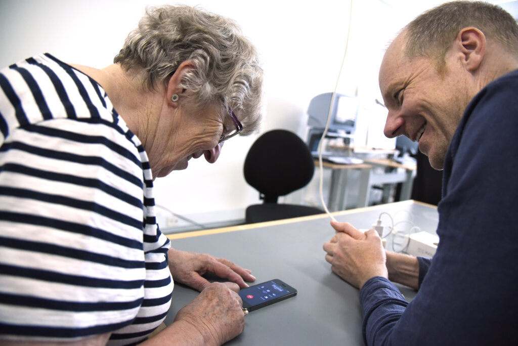 To personer sidder sammen og kigger på en mobiltelefon